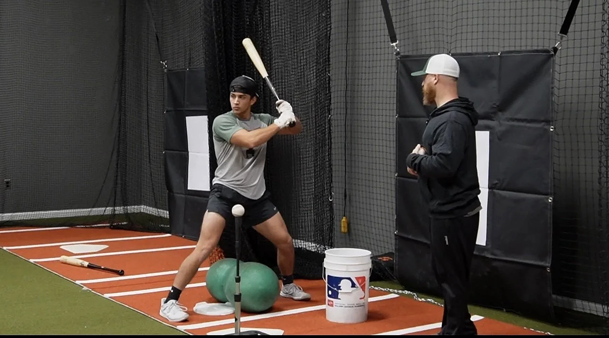 Hitter training in an indoor cage with a Full Depth coach